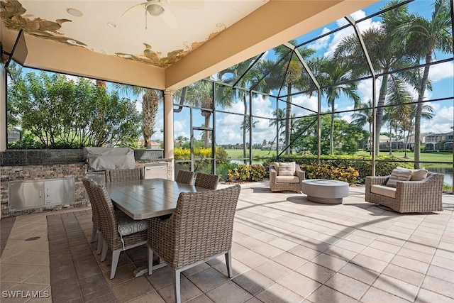 view of patio / terrace with area for grilling, glass enclosure, and ceiling fan