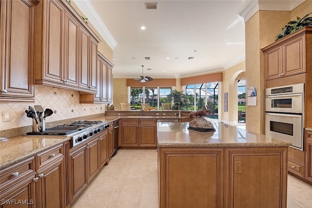 kitchen with light tile patterned floors, a kitchen island, double oven, and ornamental molding