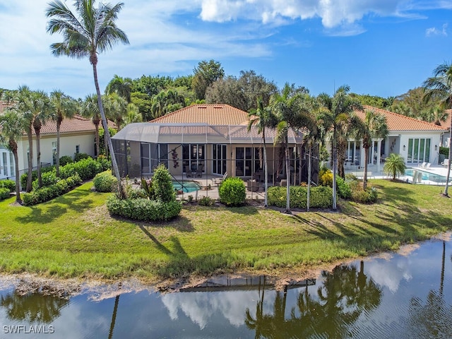 rear view of house featuring a water view and a lawn