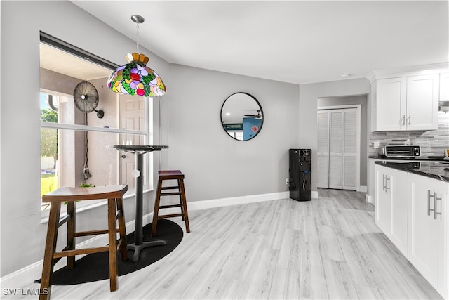 kitchen with backsplash, white cabinets, and light wood-type flooring