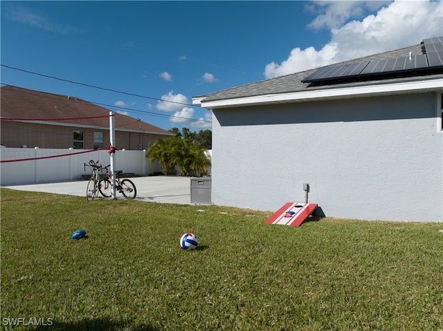 view of side of home featuring a yard, a patio area, and solar panels