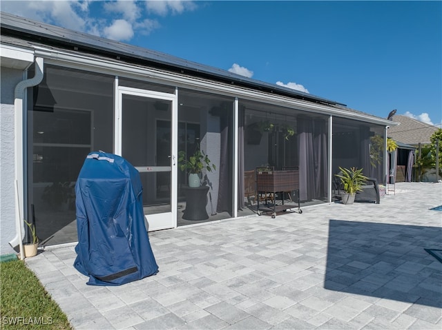 rear view of house featuring a sunroom, a patio area, and solar panels