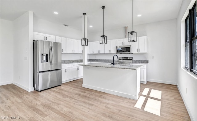 kitchen featuring white cabinetry, an island with sink, light stone countertops, and appliances with stainless steel finishes