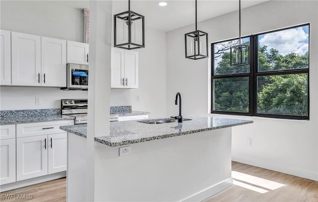 kitchen featuring stainless steel appliances, a kitchen island with sink, white cabinets, and pendant lighting