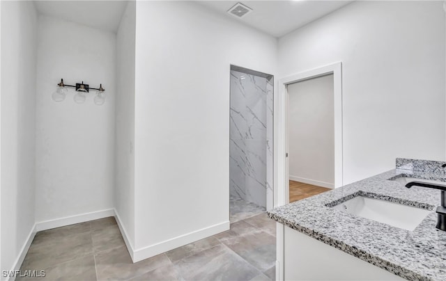 bathroom featuring a tile shower, tile patterned flooring, and vanity