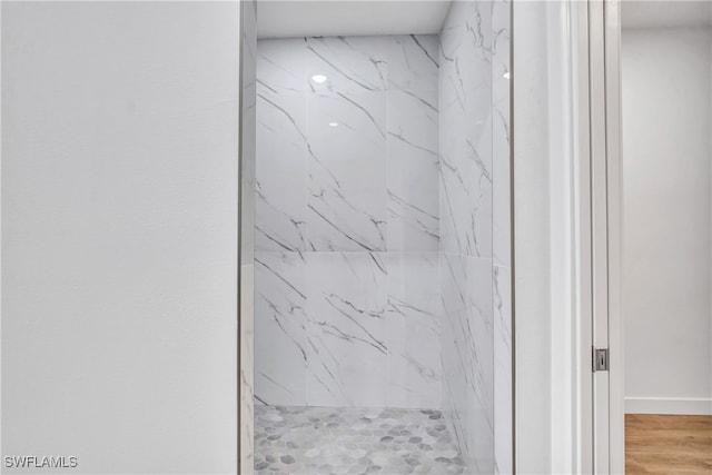 room details with tiled shower and wood-type flooring