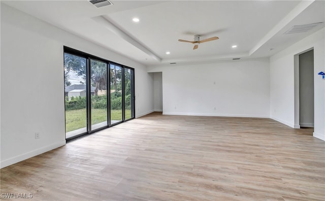 spare room with light wood-type flooring, a raised ceiling, and ceiling fan