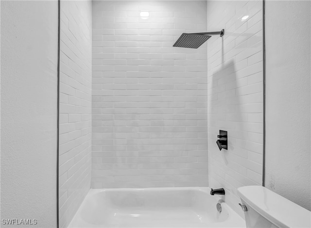 bathroom with tiled shower / bath combo and toilet