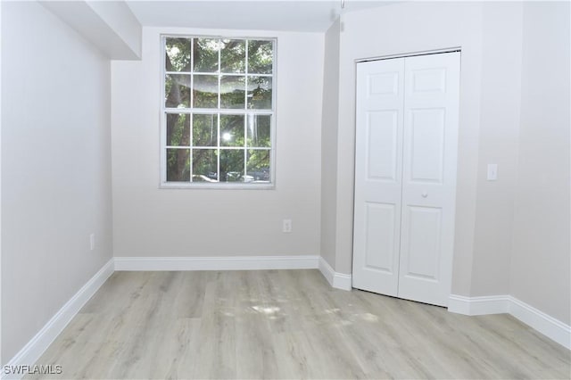 unfurnished bedroom with a closet, multiple windows, and light wood-type flooring