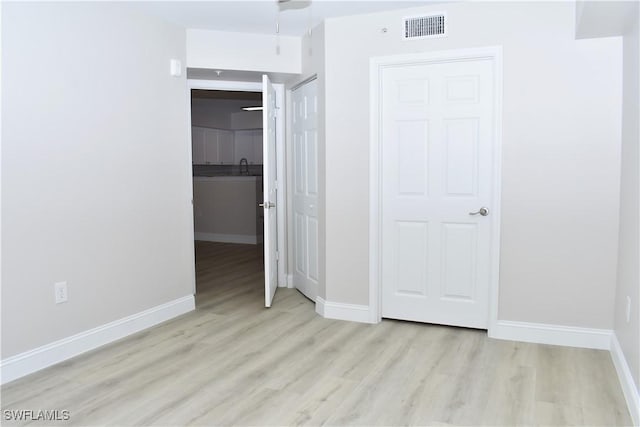 unfurnished bedroom with light hardwood / wood-style flooring and a closet