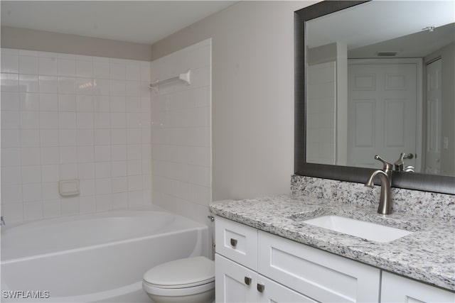 full bathroom with tiled shower / bath, vanity, and toilet