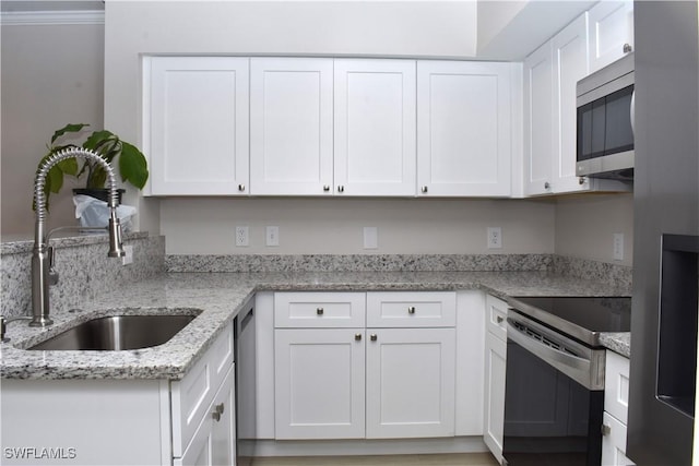 kitchen featuring light stone countertops, sink, ornamental molding, white cabinetry, and appliances with stainless steel finishes