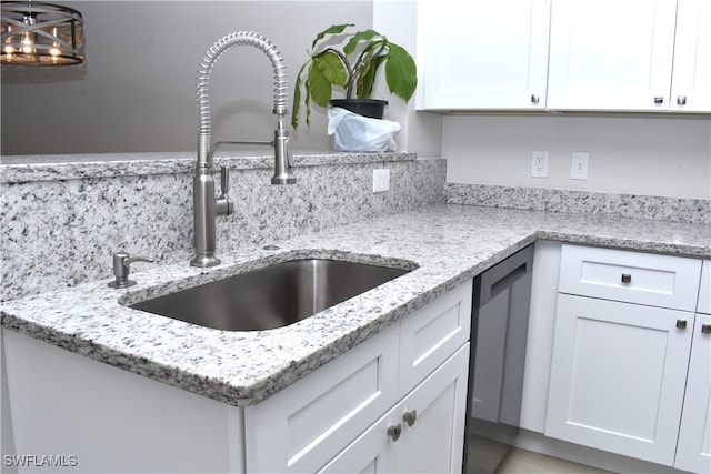 kitchen featuring light stone counters, white cabinets, sink, stainless steel dishwasher, and backsplash