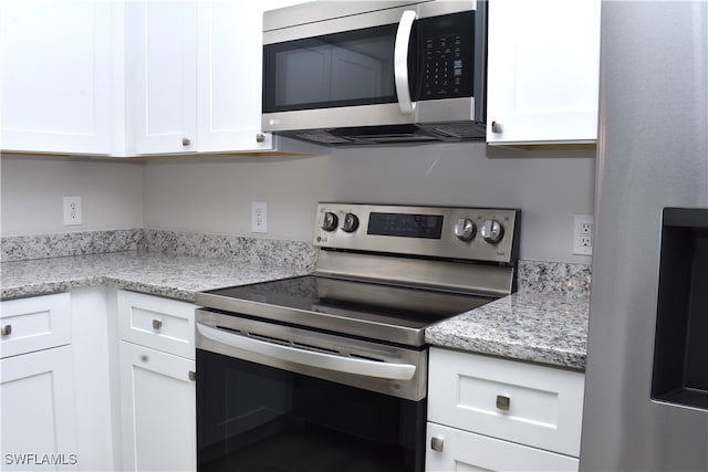 kitchen featuring light stone counters, appliances with stainless steel finishes, and white cabinetry