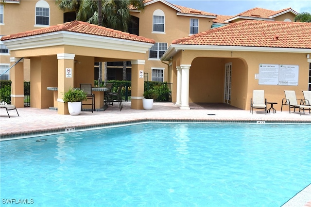 back of house with a community pool and a patio area