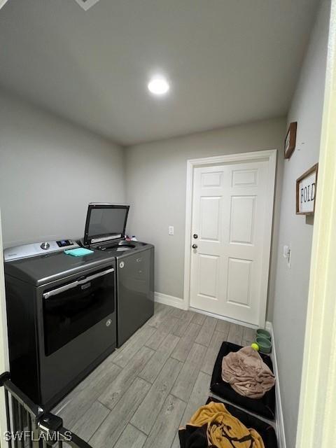 washroom with washing machine and dryer and light hardwood / wood-style flooring