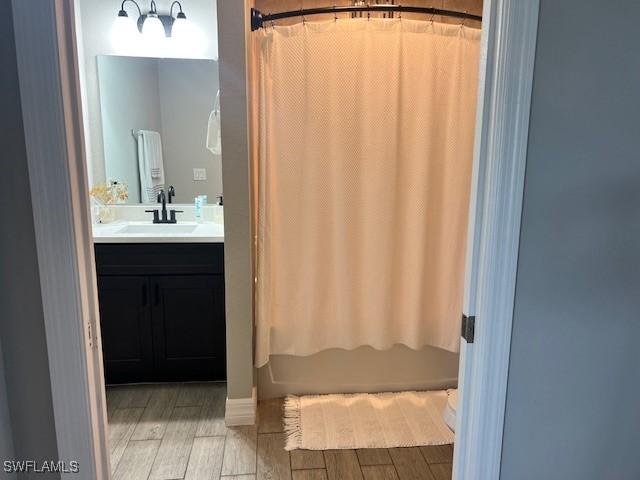 bathroom featuring hardwood / wood-style floors, vanity, and shower / bathtub combination with curtain