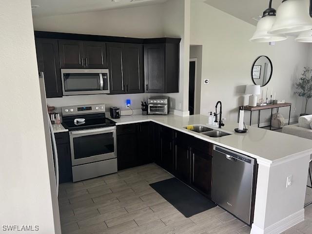 kitchen featuring kitchen peninsula, sink, lofted ceiling, and stainless steel appliances