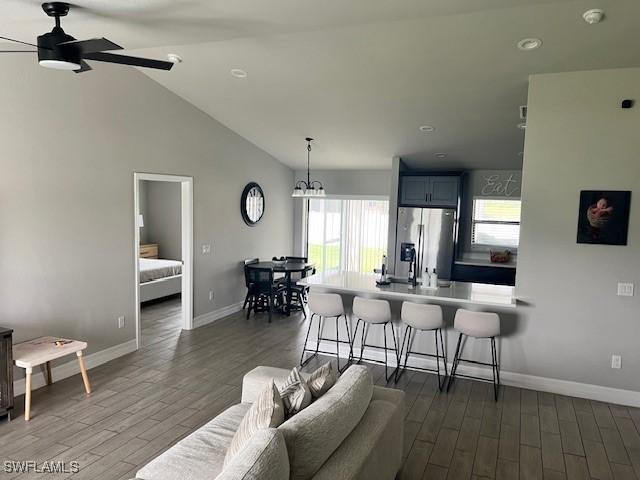 living room featuring vaulted ceiling, ceiling fan, and dark wood-type flooring