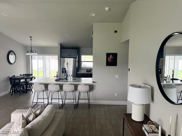 kitchen featuring dark hardwood / wood-style flooring, a breakfast bar, a healthy amount of sunlight, and stainless steel refrigerator with ice dispenser