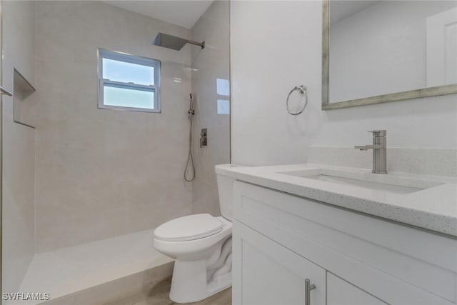 bathroom with hardwood / wood-style flooring, vanity, toilet, and a tile shower