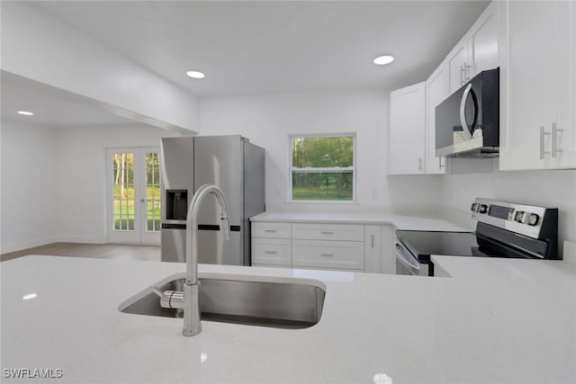 kitchen featuring plenty of natural light, white cabinets, stainless steel appliances, and sink