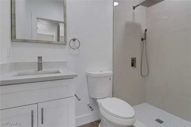 bathroom featuring a tile shower, vanity, and toilet