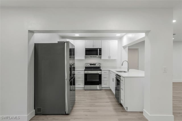 kitchen featuring white cabinetry, sink, light wood-type flooring, and appliances with stainless steel finishes