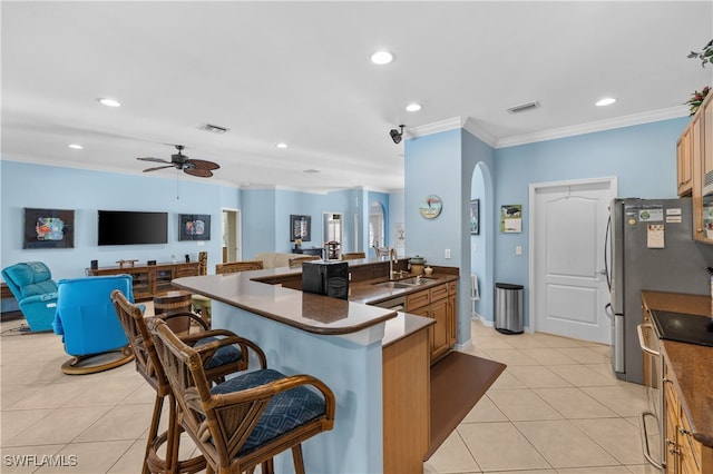 kitchen with a breakfast bar, a center island with sink, sink, stainless steel electric range oven, and ornamental molding