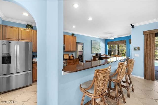 kitchen with a kitchen breakfast bar, crown molding, ceiling fan, and stainless steel refrigerator with ice dispenser