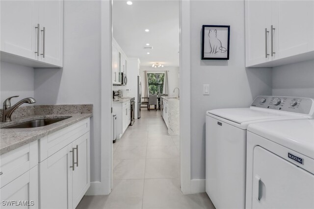 laundry area featuring light tile patterned floors, sink, independent washer and dryer, and cabinets