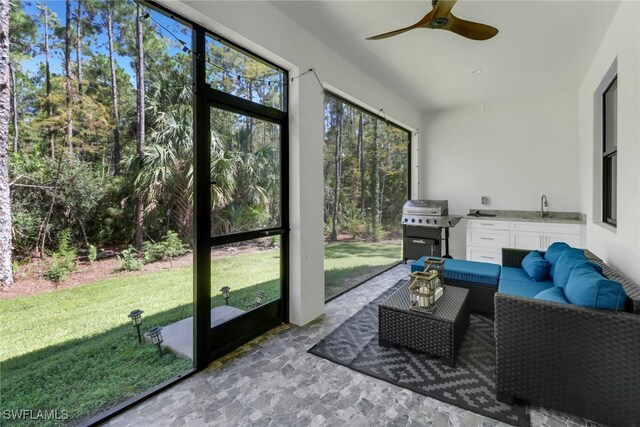 sunroom with a healthy amount of sunlight, sink, and ceiling fan