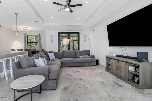 living room with a tray ceiling and ceiling fan