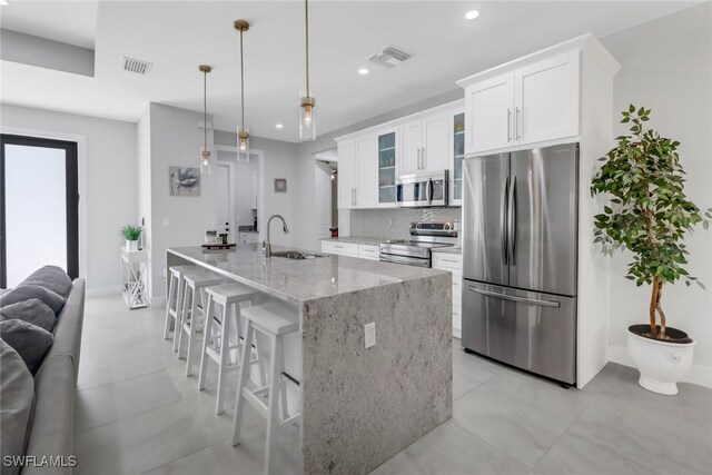 kitchen featuring decorative backsplash, white cabinets, pendant lighting, stainless steel appliances, and sink