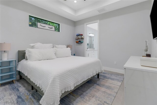 bedroom with ensuite bath and dark hardwood / wood-style floors