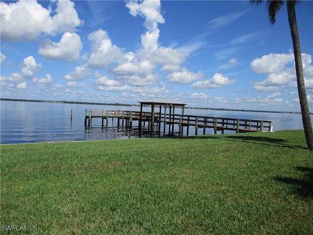 dock area with a lawn and a water view