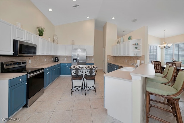 kitchen with appliances with stainless steel finishes, a breakfast bar area, blue cabinetry, sink, and a notable chandelier