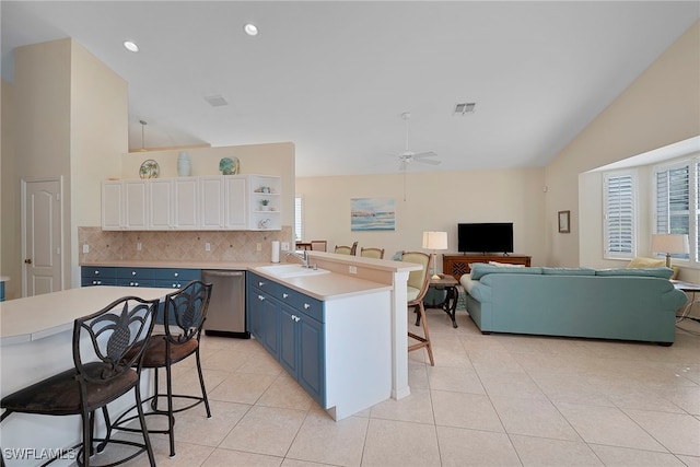 kitchen with ceiling fan, kitchen peninsula, stainless steel dishwasher, blue cabinetry, and a kitchen breakfast bar