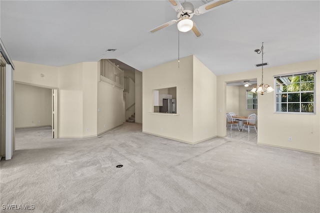 unfurnished living room featuring light carpet, ceiling fan with notable chandelier, and lofted ceiling