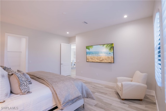 bedroom with light hardwood / wood-style flooring, multiple windows, and a walk in closet