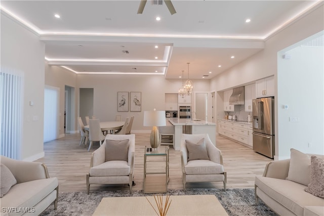 living room with ceiling fan with notable chandelier and light hardwood / wood-style flooring