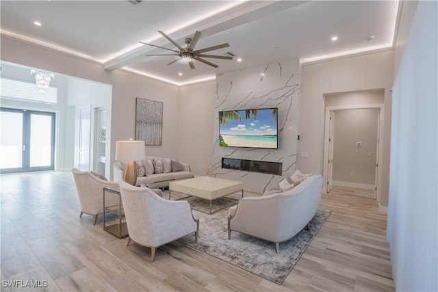 living room with light wood-type flooring, ceiling fan with notable chandelier, a fireplace, and beamed ceiling