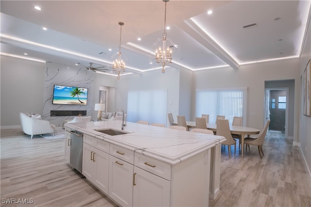 kitchen featuring sink, white cabinets, light hardwood / wood-style flooring, a center island with sink, and stainless steel dishwasher