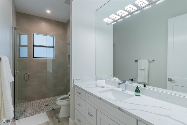 bathroom featuring wood-type flooring, an enclosed shower, vanity, and toilet