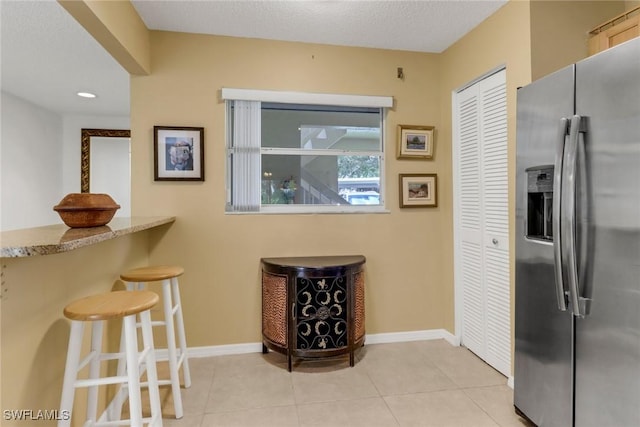 kitchen featuring stainless steel refrigerator with ice dispenser, a textured ceiling, and light tile patterned flooring