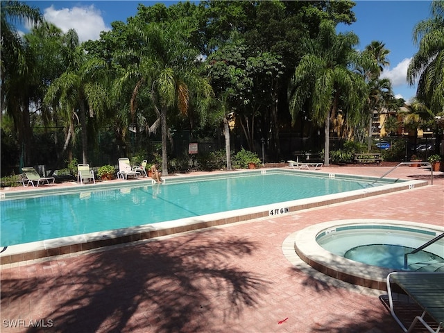 view of swimming pool featuring a hot tub and a patio area