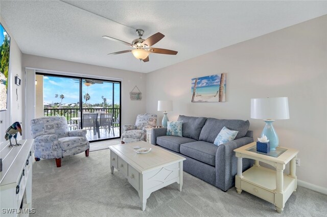 living room with a textured ceiling, ceiling fan, and light colored carpet