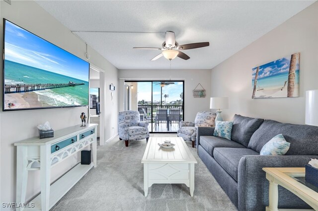 living room featuring ceiling fan, light colored carpet, and a textured ceiling