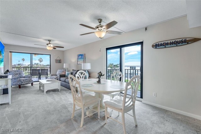 dining room with a textured ceiling, ceiling fan, and light colored carpet