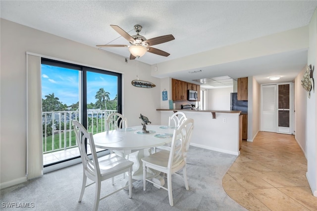 dining space with light carpet, ceiling fan, and a textured ceiling